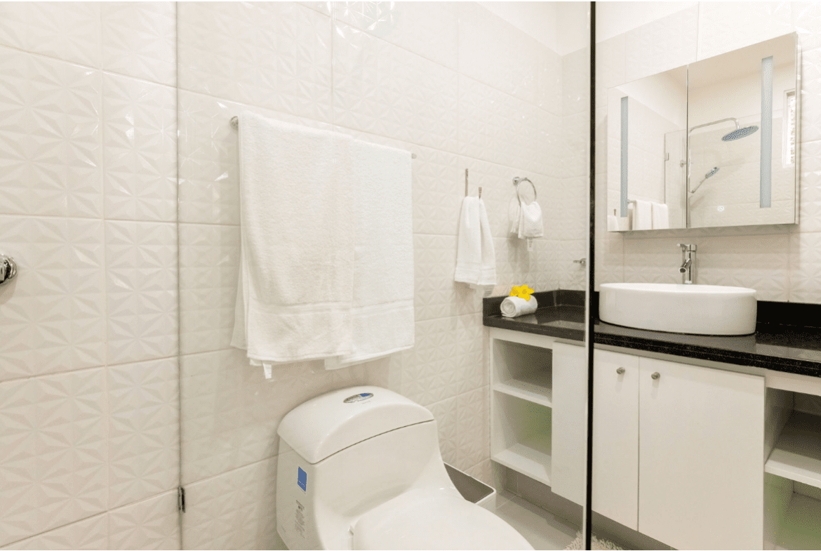 buyDRproperty Modern bathroom with white tiles, towel rack, and white toilet. Part of a gorgeous 5 bedroom villa. Sosua Real Estate
