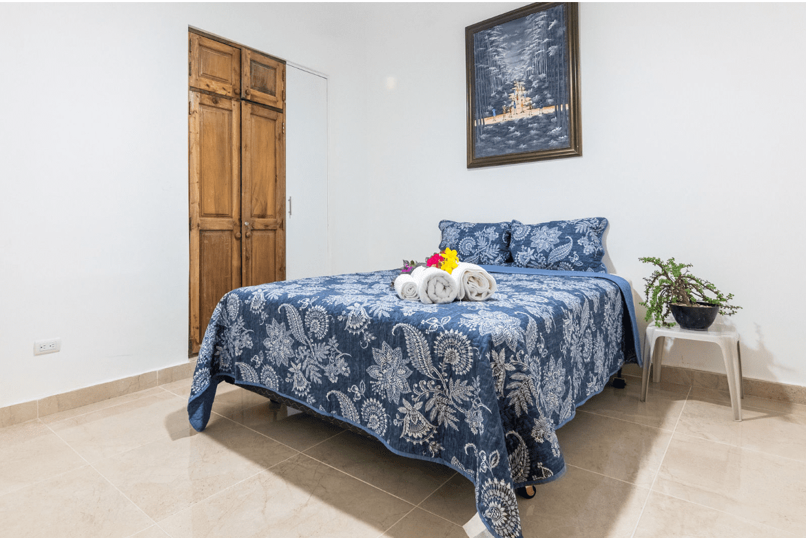 buyDRproperty Bedroom in a Gorgeous 5 Bedroom Villa with blue patterned quilt and wooden wardrobe. Sosua Real Estate