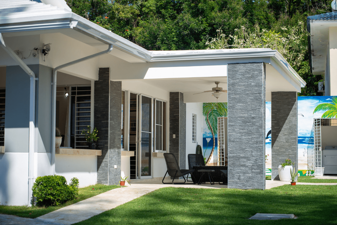 buyDRproperty Gorgeous 5 Bedroom Villa exterior with covered patio and lush green lawn Sosua Real Estate
