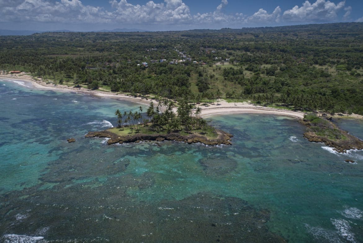 buyDRproperty Aerial view of oceanfront development property with potential marina, featuring a small island and turquoise waters. Sosua Real Estate