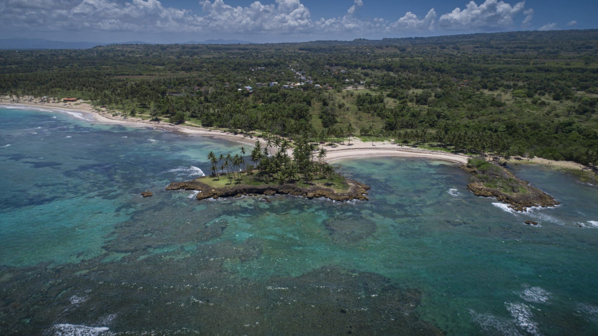 buyDRproperty Aerial view of oceanfront development property with potential marina, featuring a small island and turquoise waters. Sosua Real Estate