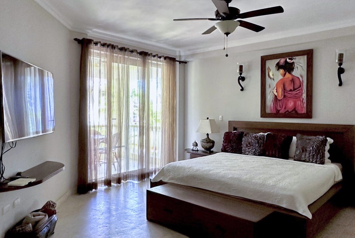 buyDRproperty Bedroom interior with a bed, TV, and sheer curtains. Sosua Real Estate