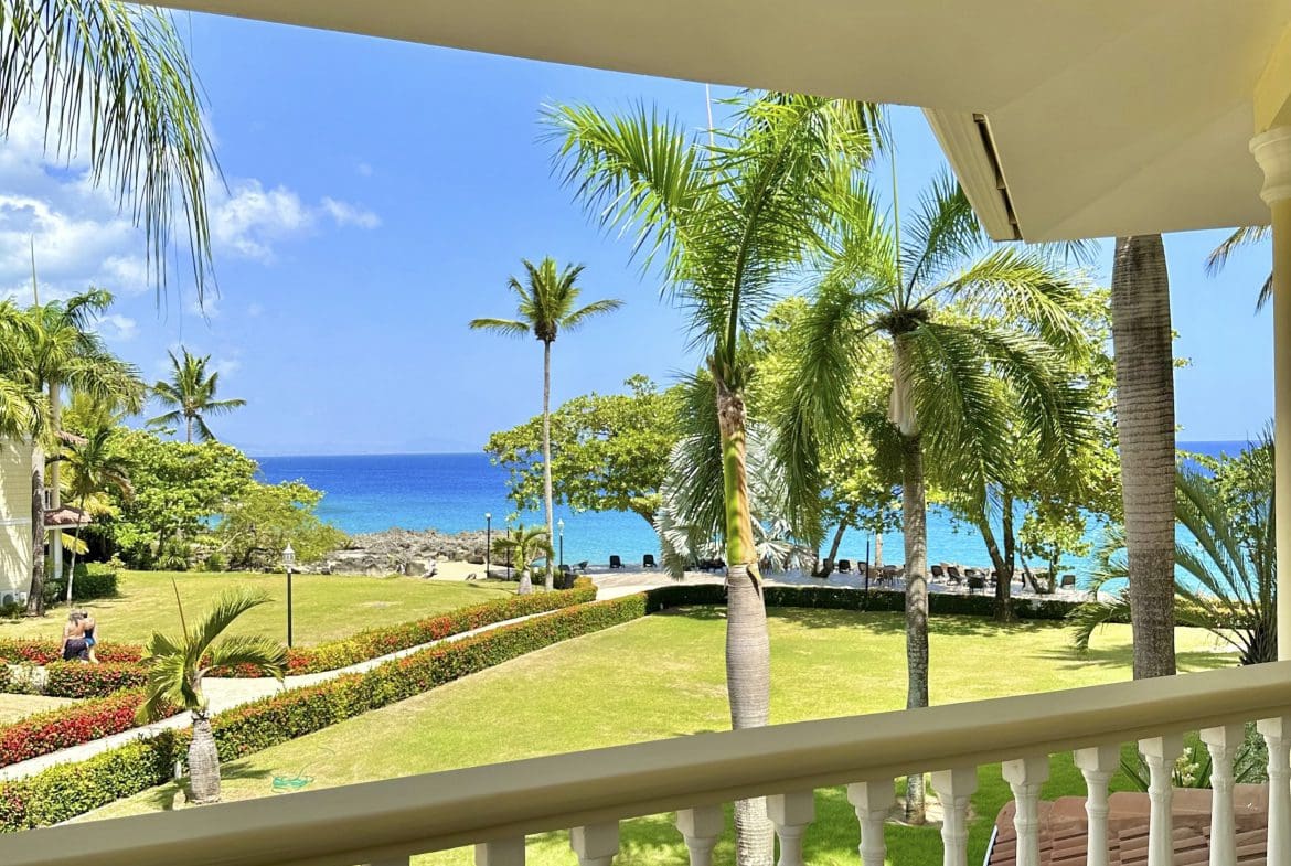 buyDRproperty Ocean view from a balcony in Sosua, Dominican Republic; palm trees and turquoise water. Sosua Real Estate