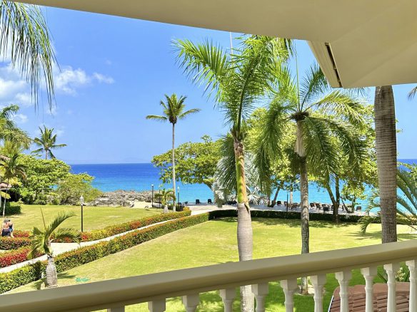 buyDRproperty Ocean view from a balcony in Sosua, Dominican Republic; palm trees and turquoise water. Sosua Real Estate