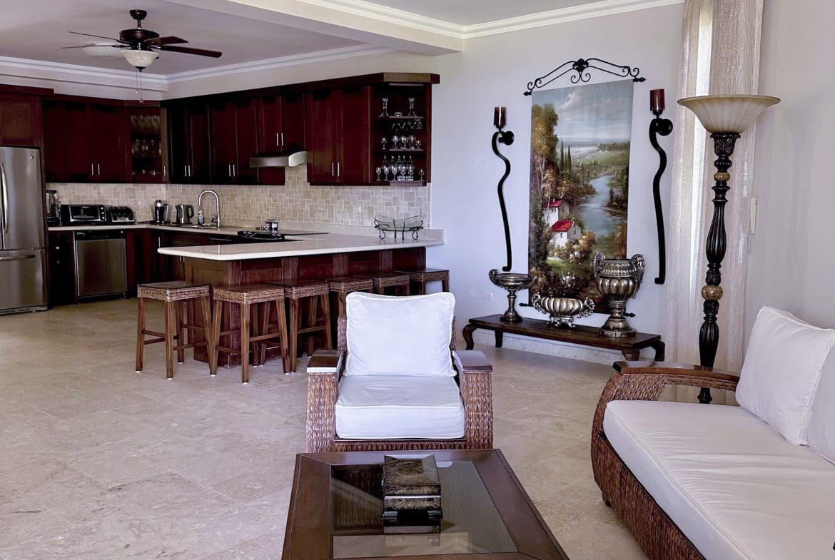 buyDRproperty Open-concept living area with kitchen and seating in a Sosua condo for sale. Sosua Real Estate