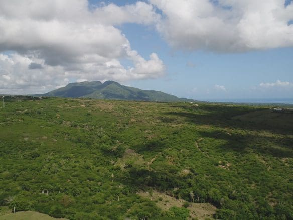 buyDRproperty Aerial view of lush green landscape in Dominica with mountains and cloudy sky Sosua Real Estate