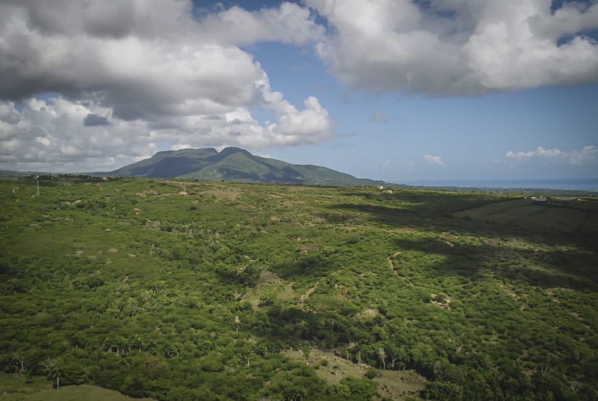 buyDRproperty Scenic view of green development property with mountain and clouds. Sosua Real Estate