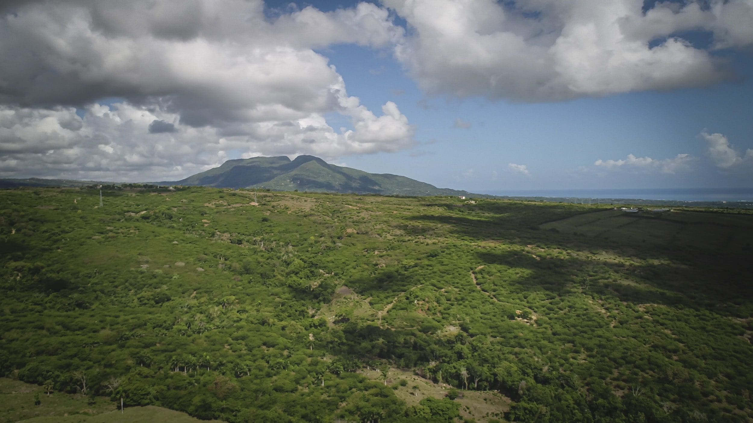 buyDRproperty Scenic view of green development property with mountain and clouds. Sosua Real Estate