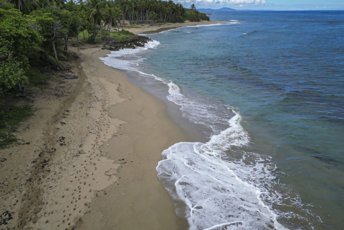 buyDRproperty Stunning oceanfront development property with beach, turquoise water, and lush green vegetation Sosua Real Estate