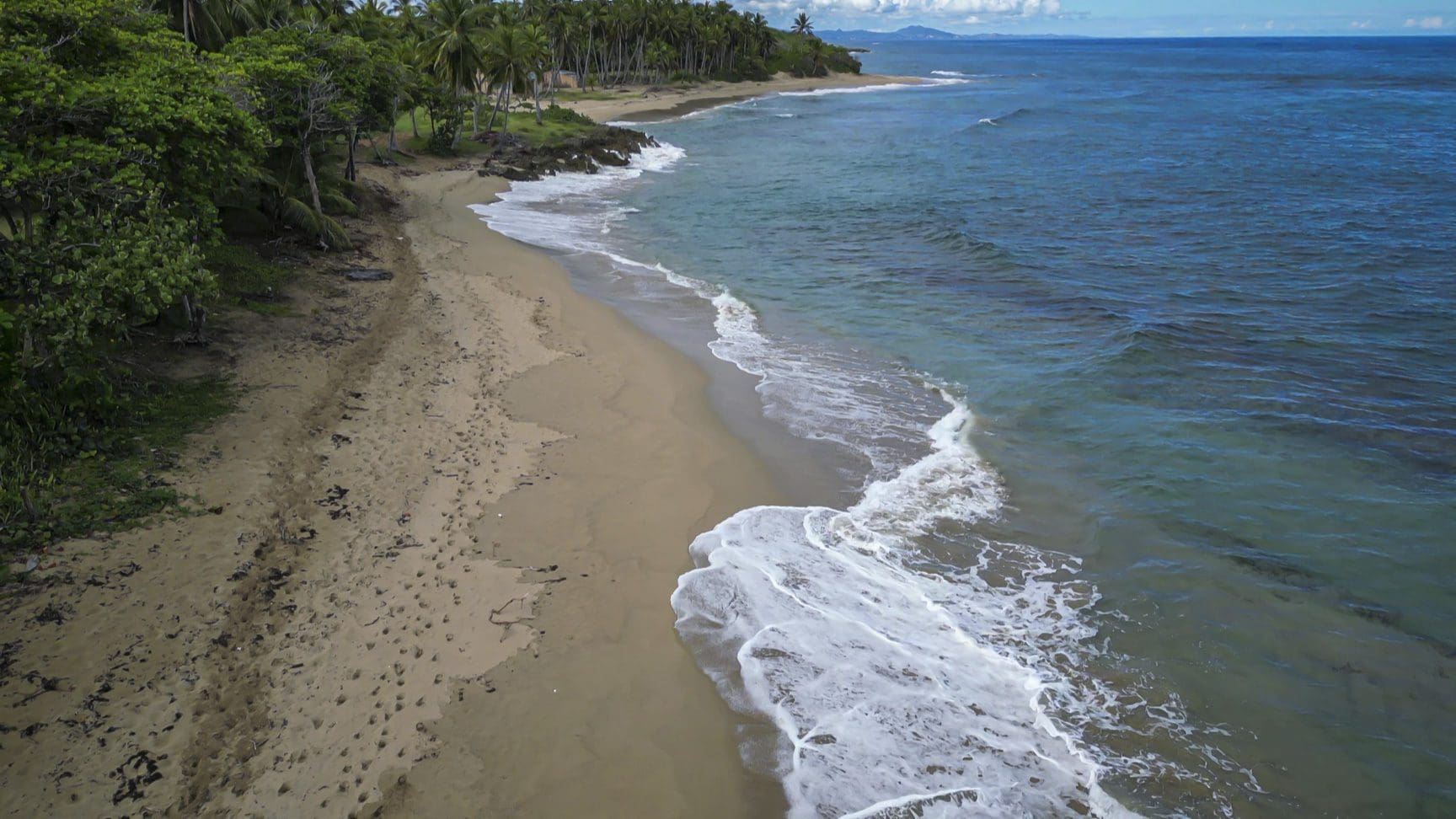 buyDRproperty Stunning oceanfront development property with beach, turquoise water, and lush green vegetation Sosua Real Estate