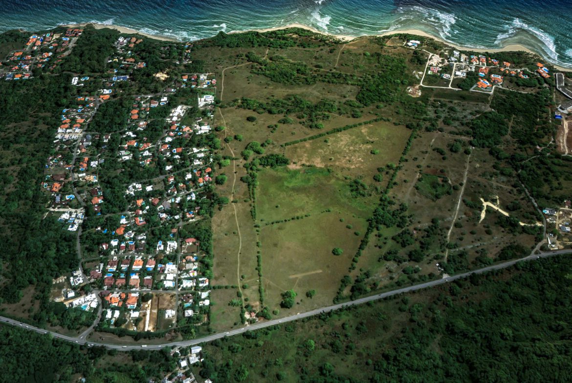 buyDRproperty Aerial view of stunning oceanfront development property with houses and undeveloped land. Sosua Real Estate