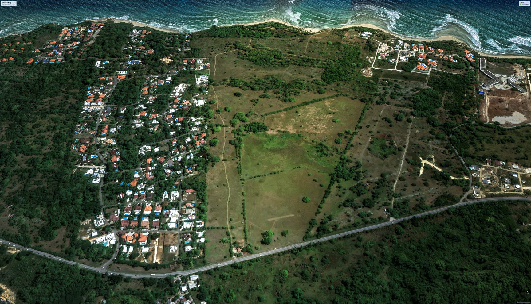 buyDRproperty Aerial view of stunning oceanfront development property with houses and undeveloped land. Sosua Real Estate