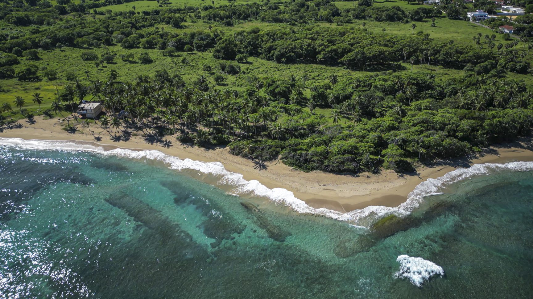 buyDRproperty Aerial view of stunning oceanfront development property with turquoise water and beach. Sosua Real Estate