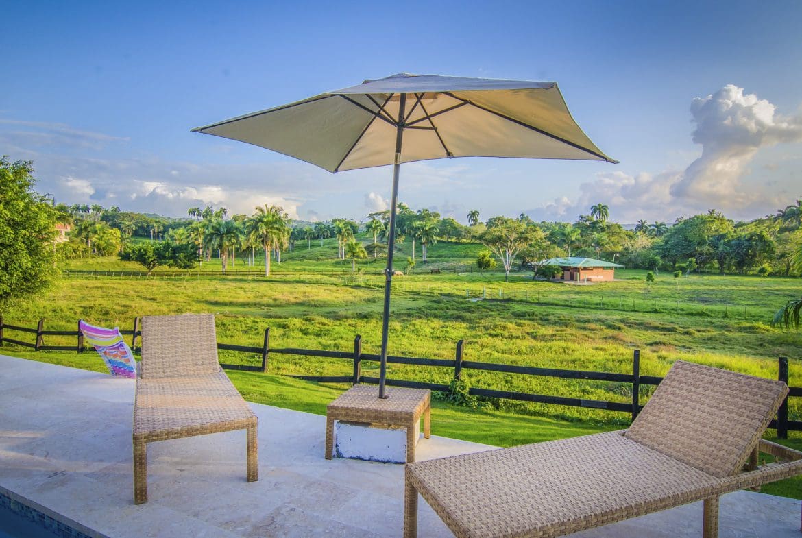 buyDRproperty Lounge chairs and umbrella overlooking a green field; perfect for a Villa For Sale in the Community Of Terramar. Sosua Real Estate