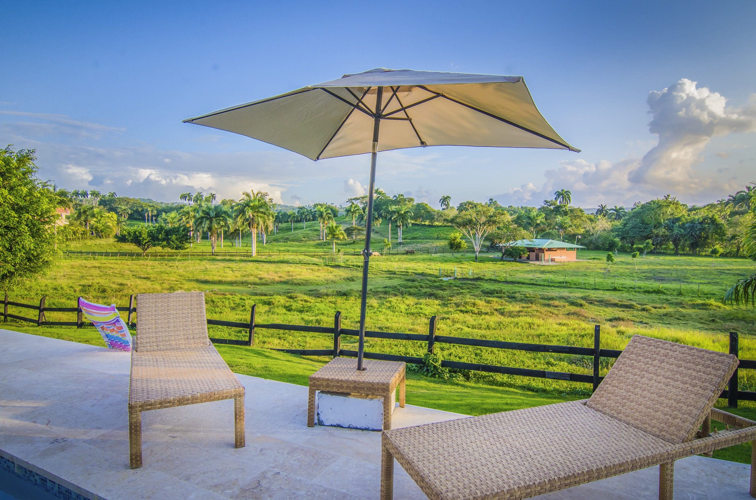 buyDRproperty Lounge chairs and umbrella overlooking a green field; perfect for a Villa For Sale in the Community Of Terramar. Sosua Real Estate