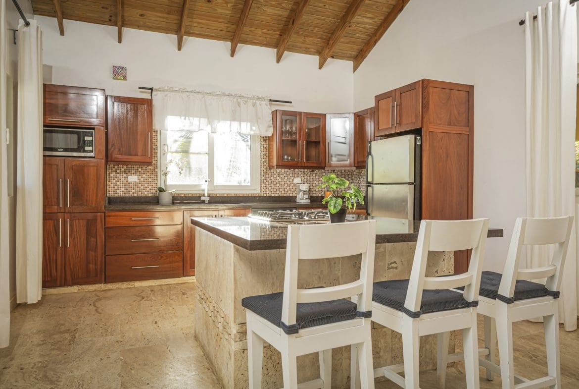 buyDRproperty Stylish kitchen with wooden cabinets and a breakfast bar. This Villa For Sale is in the Community Of Terramar. Sosua Real Estate