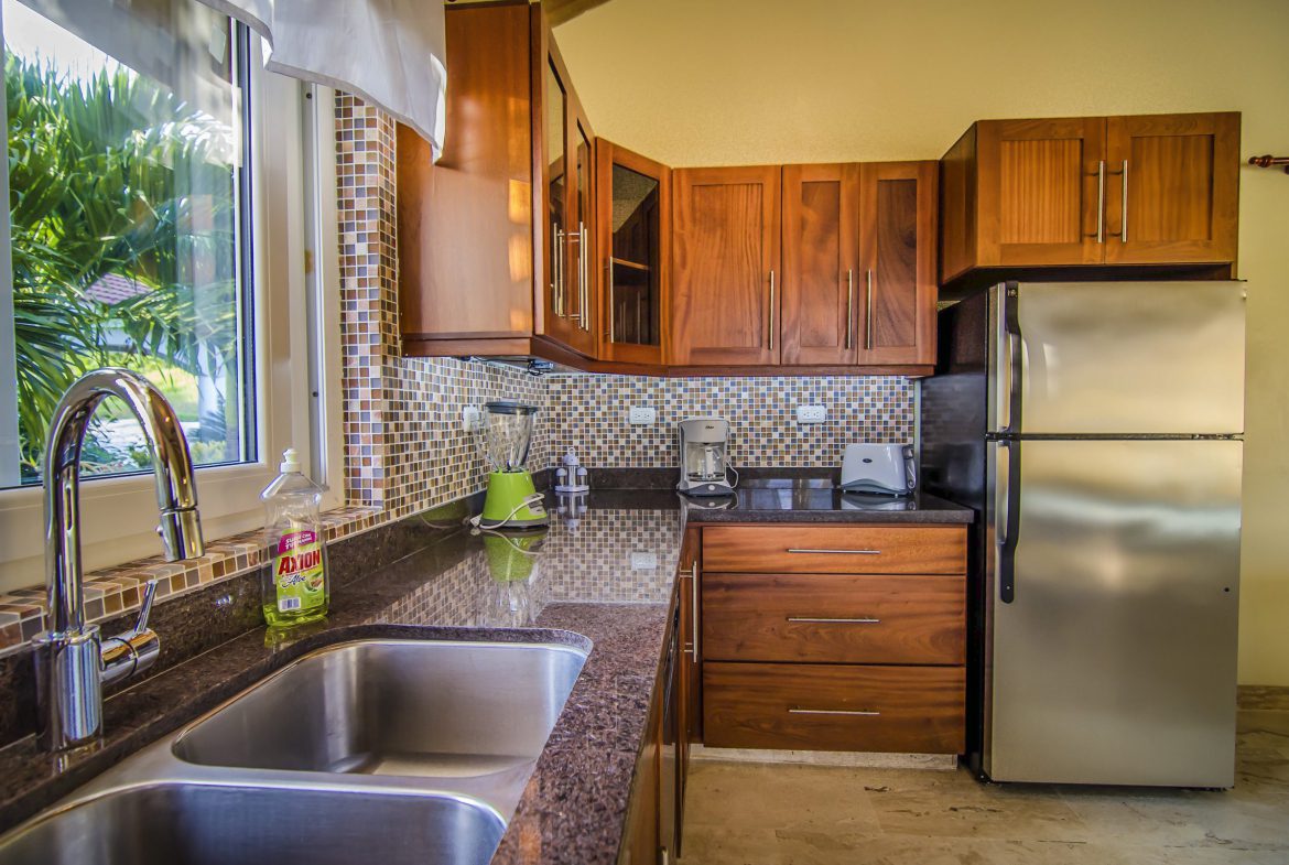 buyDRproperty Kitchen in a Villa For Sale in the Community of Terramar with wooden cabinets and stainless steel appliances. Sosua Real Estate