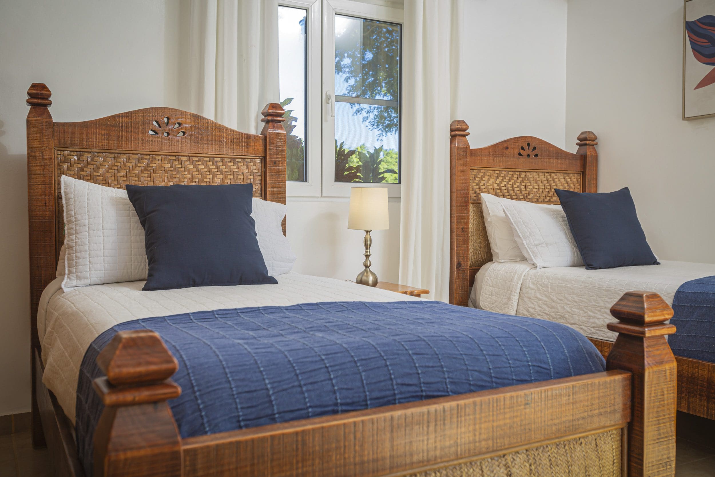 buyDRproperty Twin bedroom in a Villa For Sale. Beds with wooden frames, white bedding, and navy accents. Sosua Real Estate