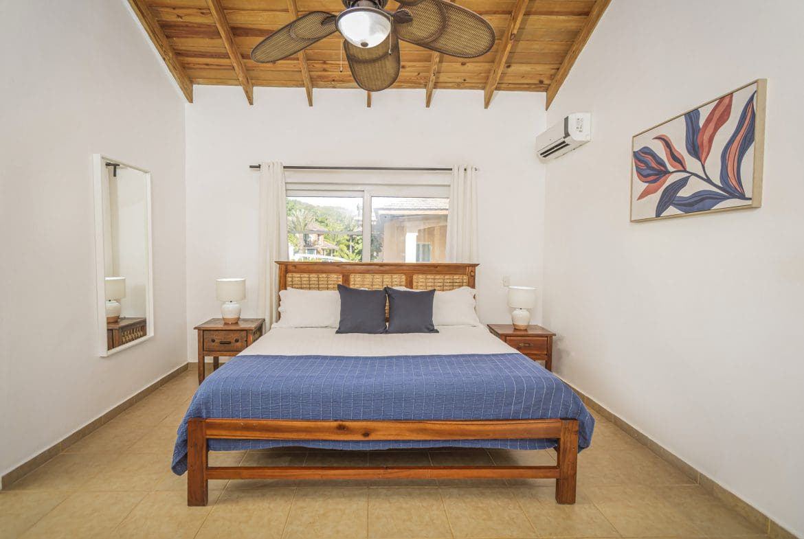 buyDRproperty Bedroom in a villa for sale in the Community of Terramar with a wooden bed frame, nightstands, and artwork. Sosua Real Estate