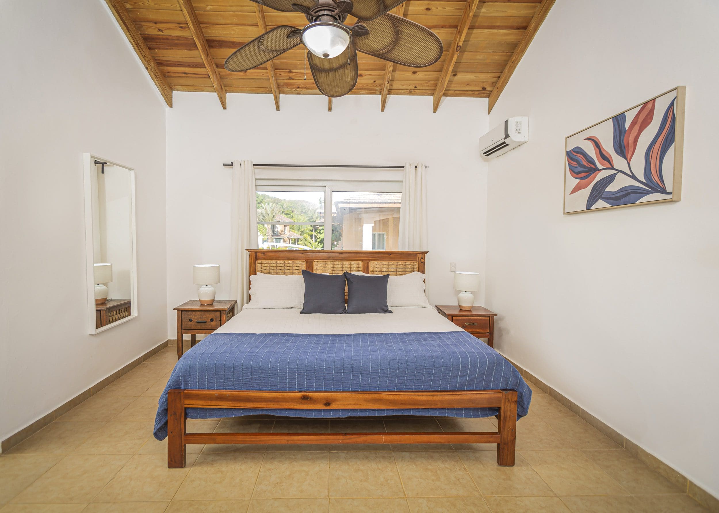 buyDRproperty Bedroom in a villa for sale in the Community of Terramar with a wooden bed frame, nightstands, and artwork. Sosua Real Estate
