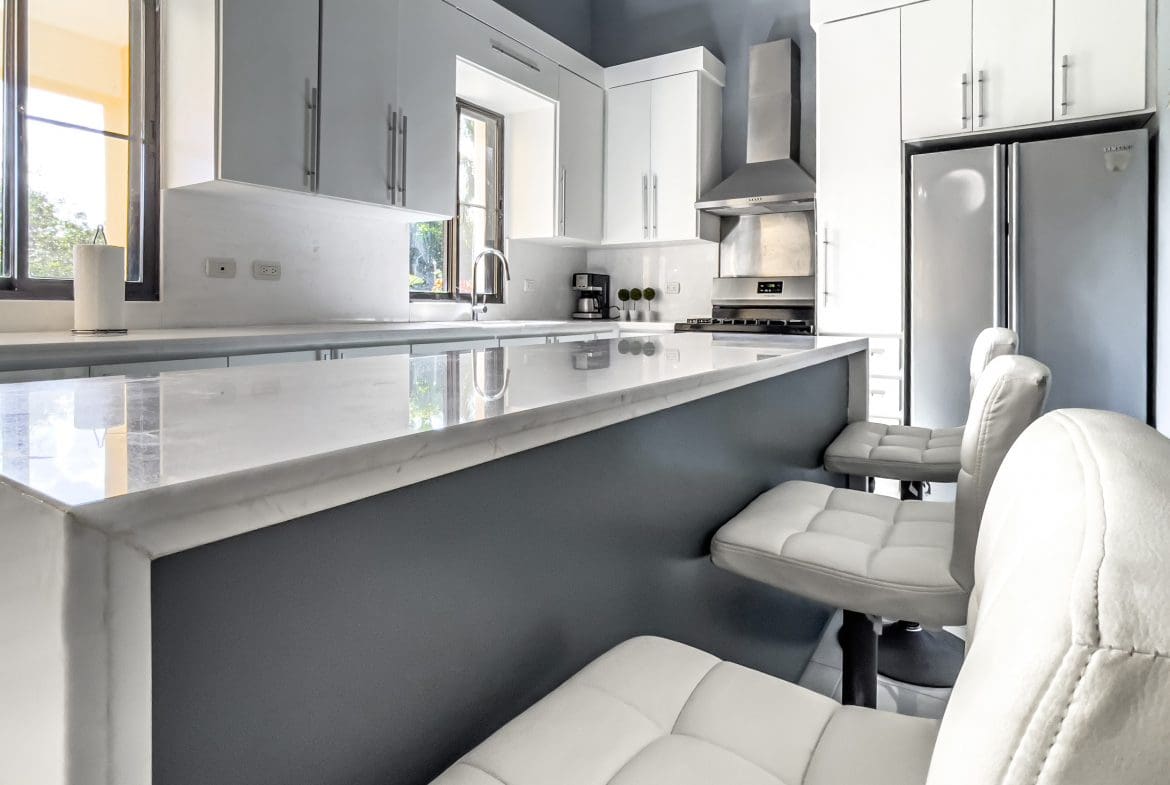 buyDRproperty Modern kitchen in a stunning 4 bedroom villa with white countertops and bar stools. Sosua Real Estate