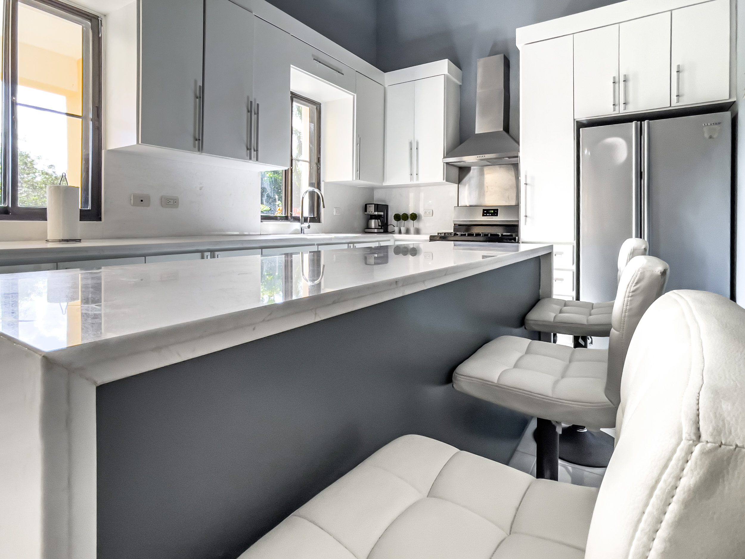buyDRproperty Modern kitchen in a stunning 4 bedroom villa with white countertops and bar stools. Sosua Real Estate