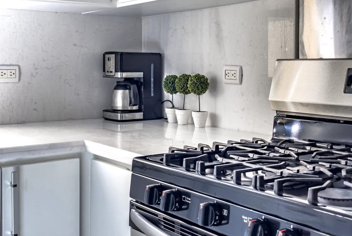 buyDRproperty Modern kitchen in a stunning 4 bedroom villa with white countertops and black stove. Sosua Real Estate