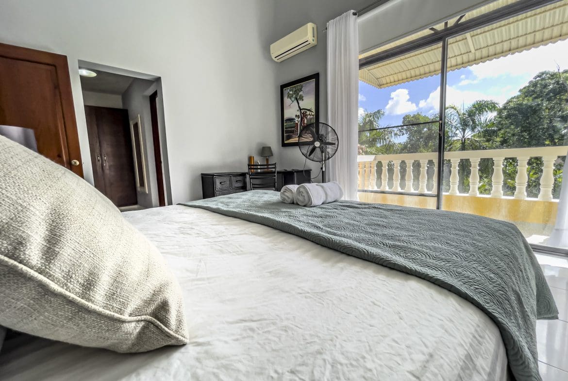 buyDRproperty Bedroom with a view in a stunning 4 bedroom villa. White sheets and teal coverlet. Sosua Real Estate