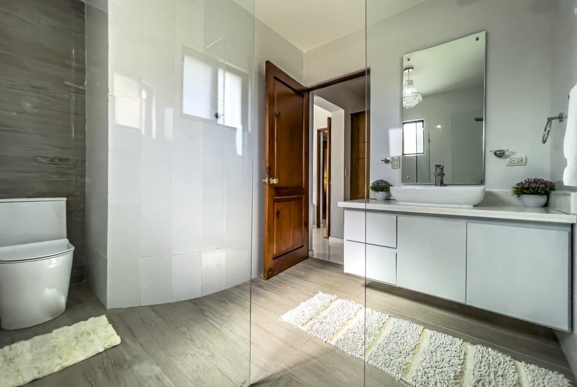 buyDRproperty Modern bathroom in a stunning 4 bedroom villa with white fixtures and glass shower. Sosua Real Estate