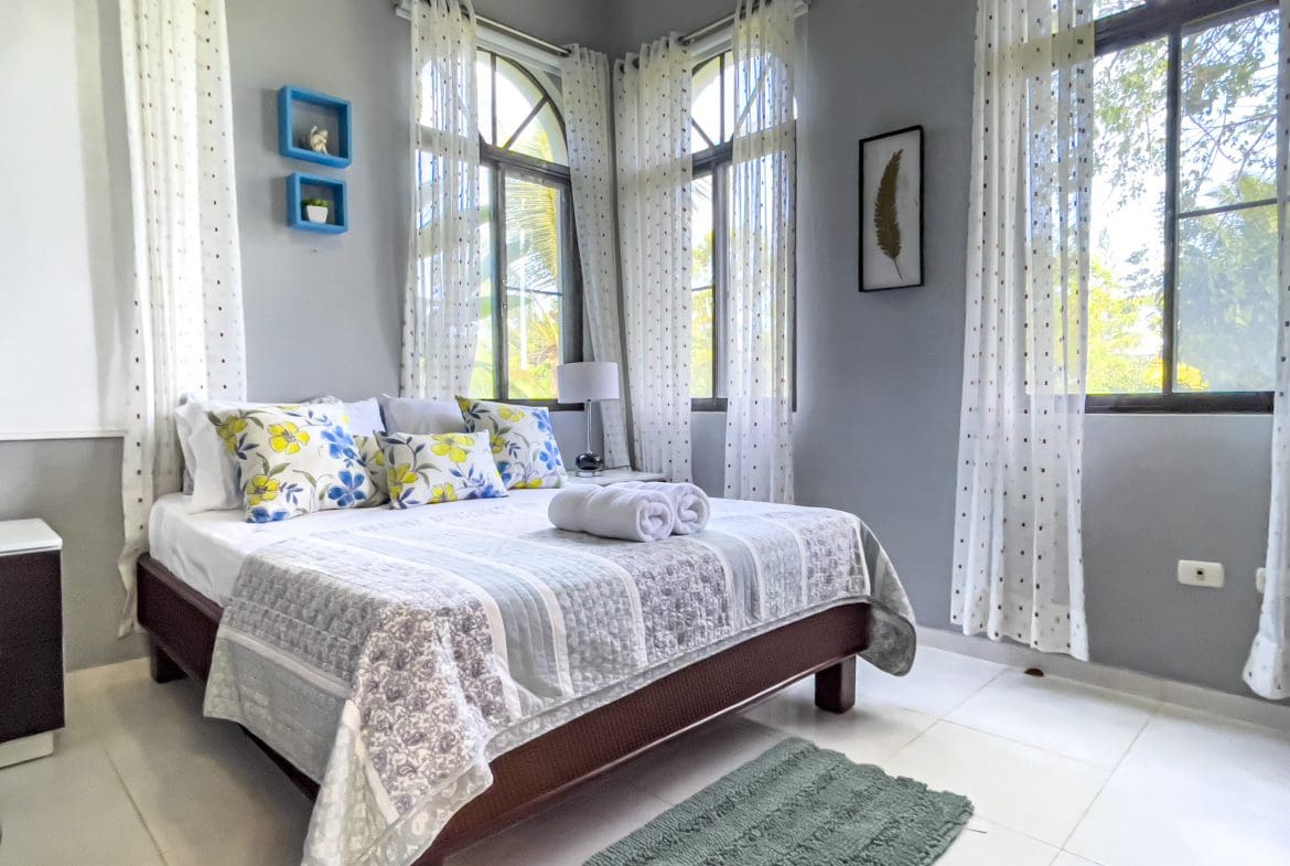 buyDRproperty Bedroom in a stunning 4 bedroom villa with floral pillows and sheer curtains. Sosua Real Estate