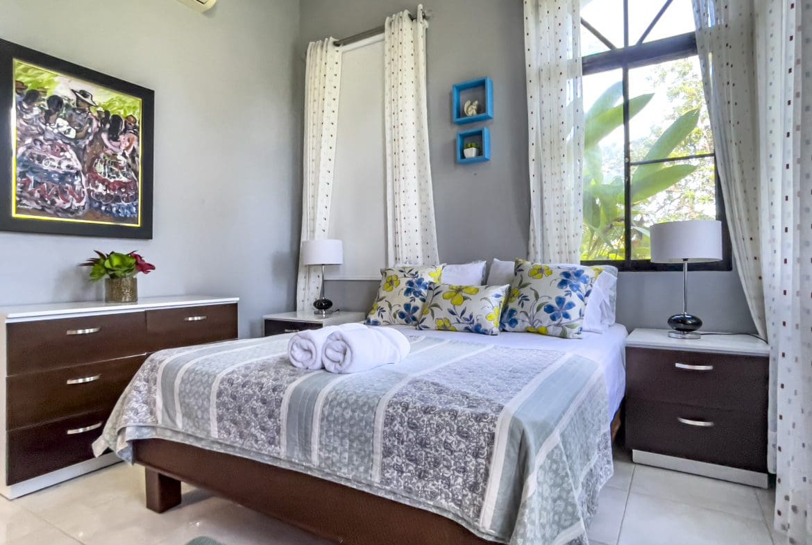 buyDRproperty Bedroom in a Stunning 4 Bedroom Villa with floral pillows and a large window. Sosua Real Estate