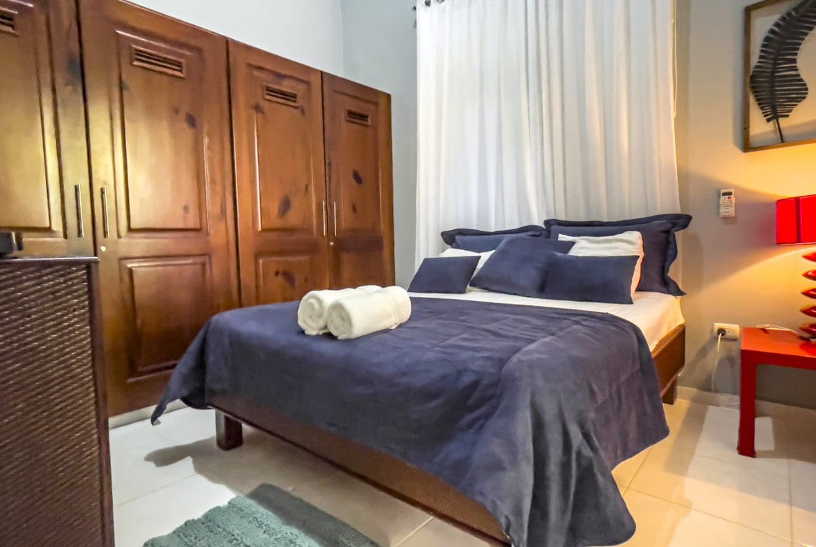 buyDRproperty Cozy bedroom in a stunning 4 bedroom villa with dark blue bedding and wooden wardrobe. Sosua Real Estate