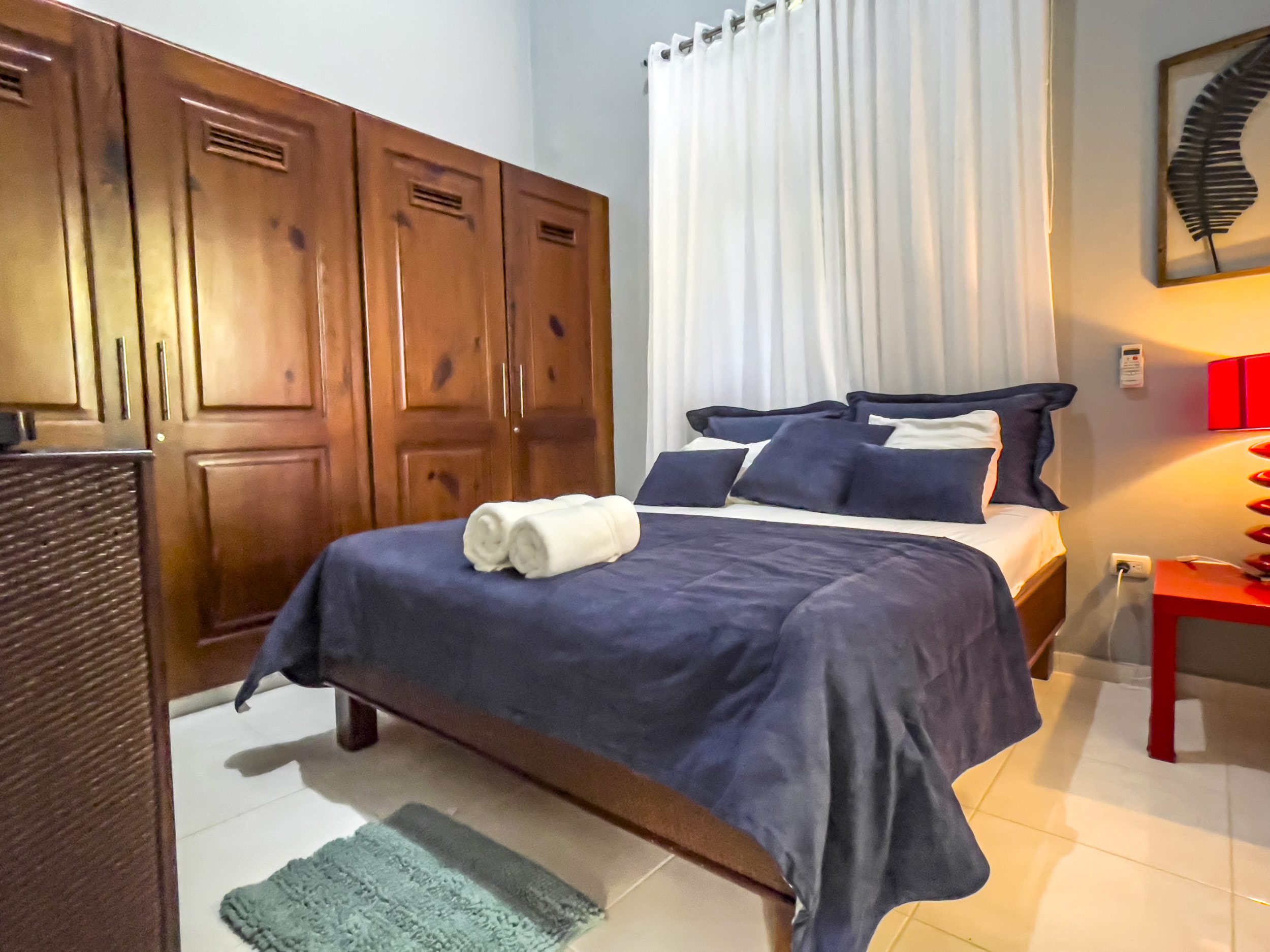 buyDRproperty Cozy bedroom in a stunning 4 bedroom villa with dark blue bedding and wooden wardrobe. Sosua Real Estate