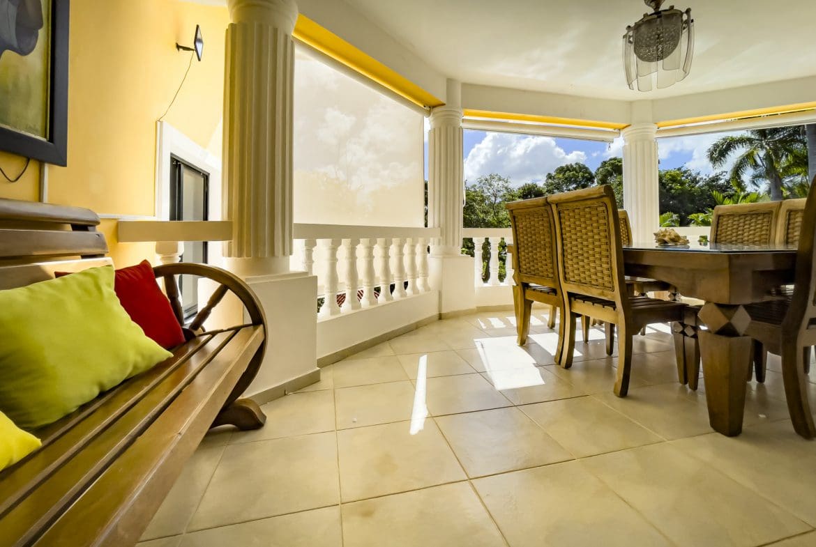 buyDRproperty Stunning 4 Bedroom Villa: Outdoor dining area with wooden table and chairs overlooking lush greenery. Sosua Real Estate