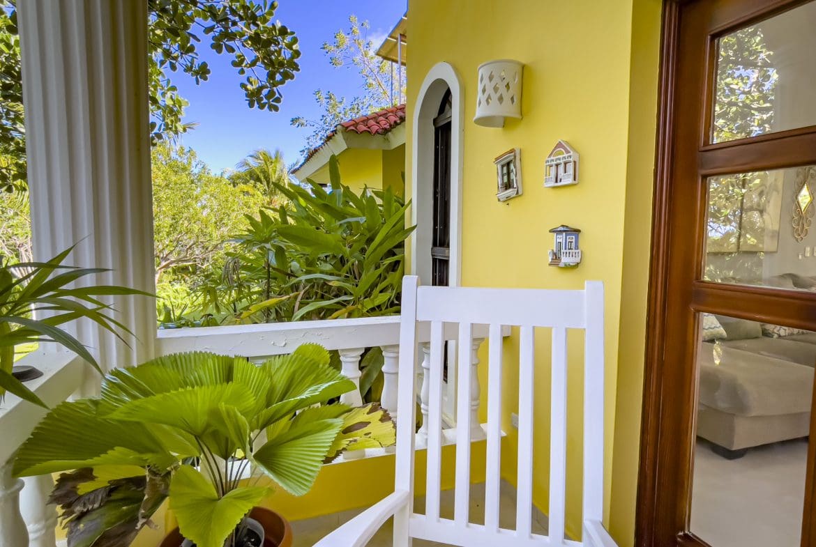 buyDRproperty Cozy porch of a stunning 4 bedroom villa with a rocking chair and greenery Sosua Real Estate