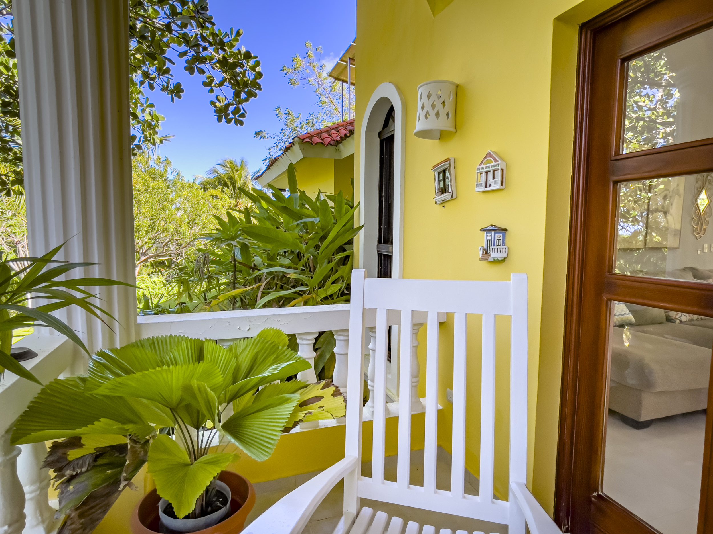 buyDRproperty Cozy porch of a stunning 4 bedroom villa with a rocking chair and greenery Sosua Real Estate