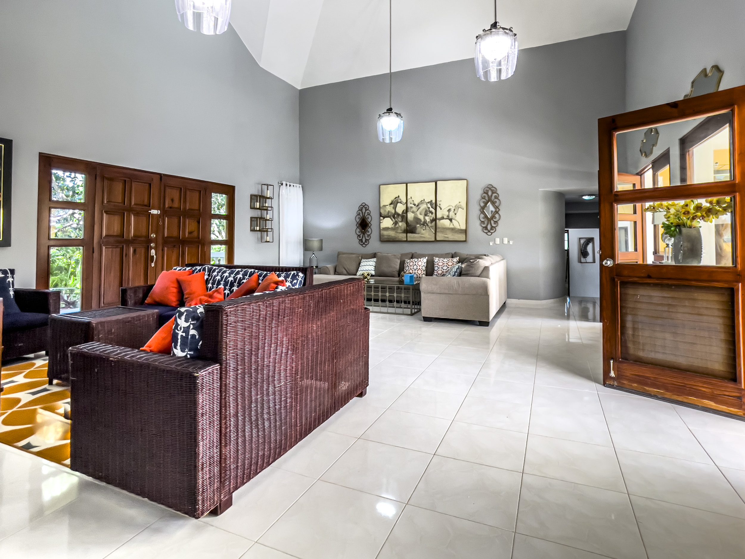 buyDRproperty Stunning 4 Bedroom Villa living room with high ceilings, wicker furniture, and a large wooden door. Sosua Real Estate
