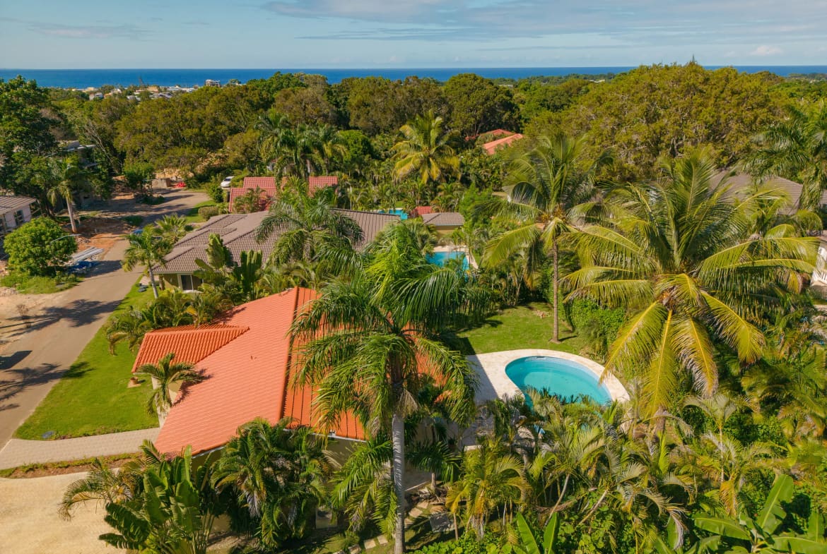 buyDRproperty Aerial view of a Renovated Villa CAOBA with a pool in Residencial Hispaniola, surrounded by lush tropical vegetation, with ocean views. Sosua Real Estate