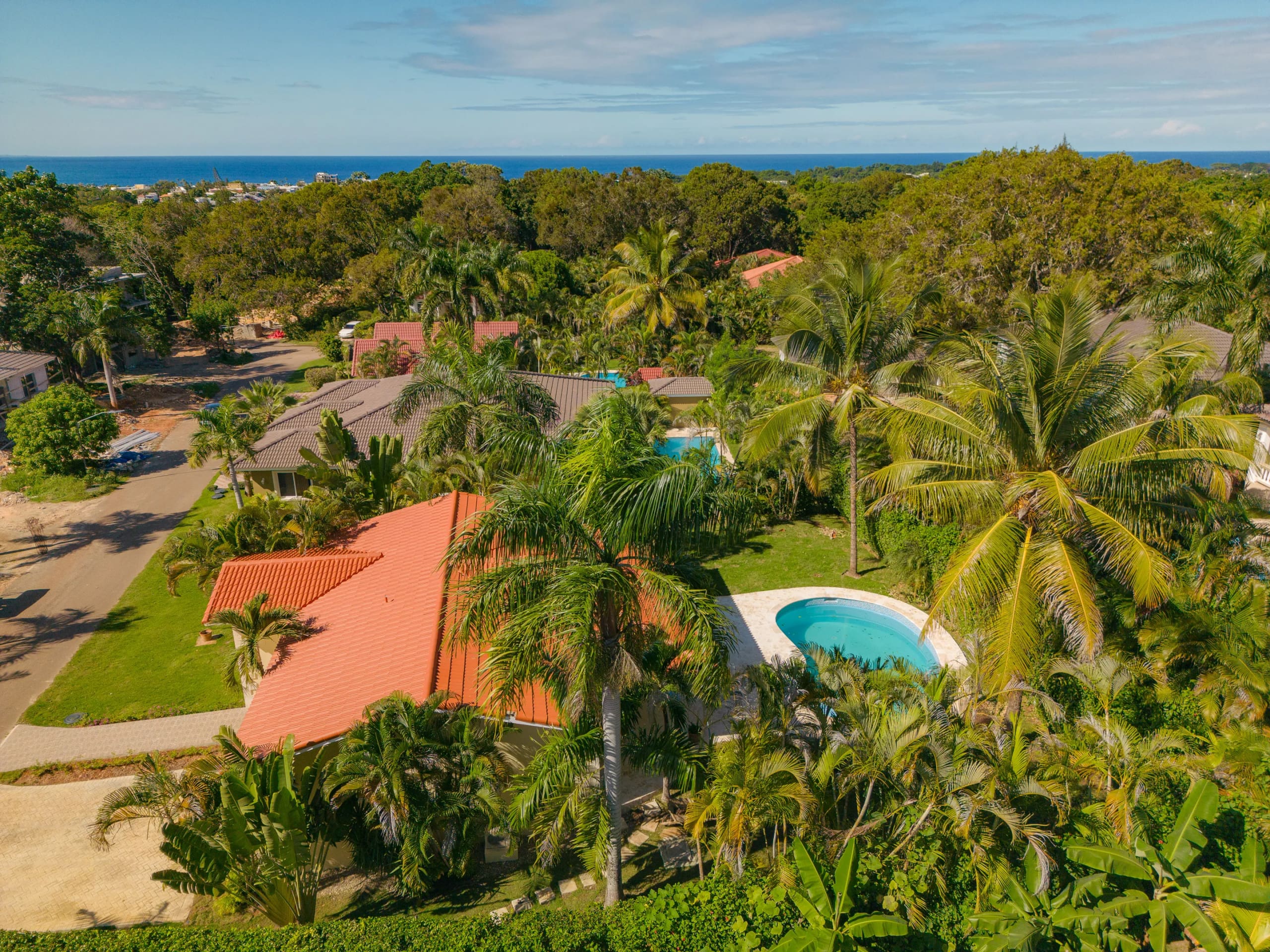 buyDRproperty Aerial view of a Renovated Villa CAOBA with a pool in Residencial Hispaniola, surrounded by lush tropical vegetation, with ocean views. Sosua Real Estate