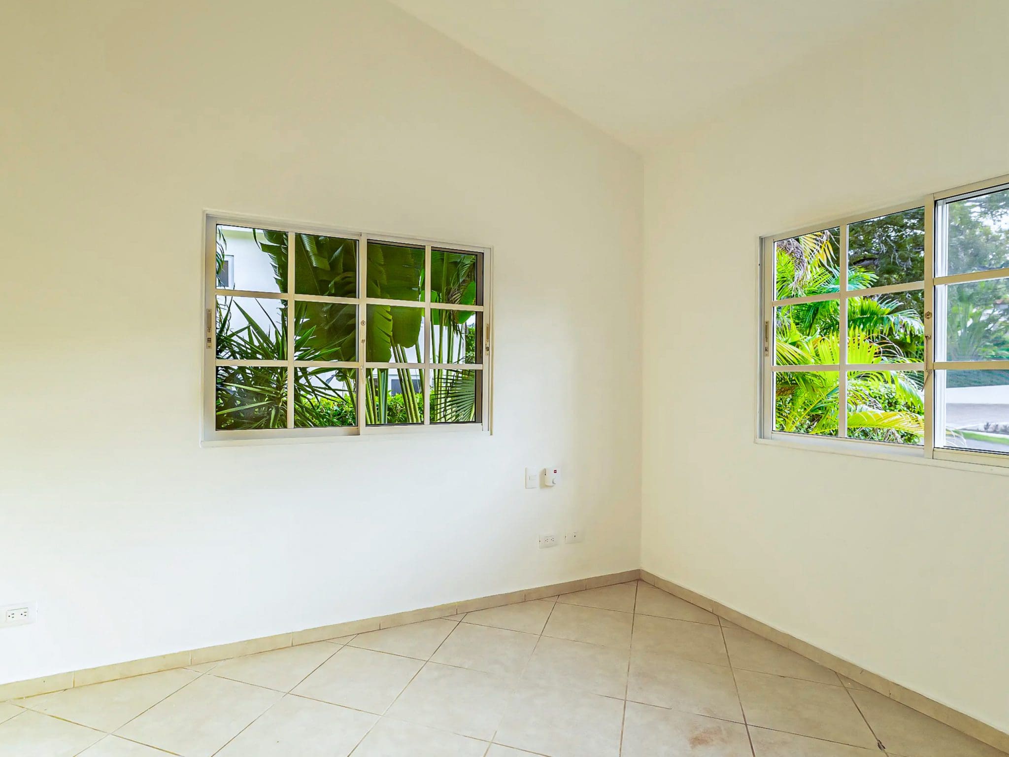 buyDRproperty Empty room with windows overlooking lush greenery. Renovated Villa CAOBA in Residencial Hispaniola. Sosua Real Estate