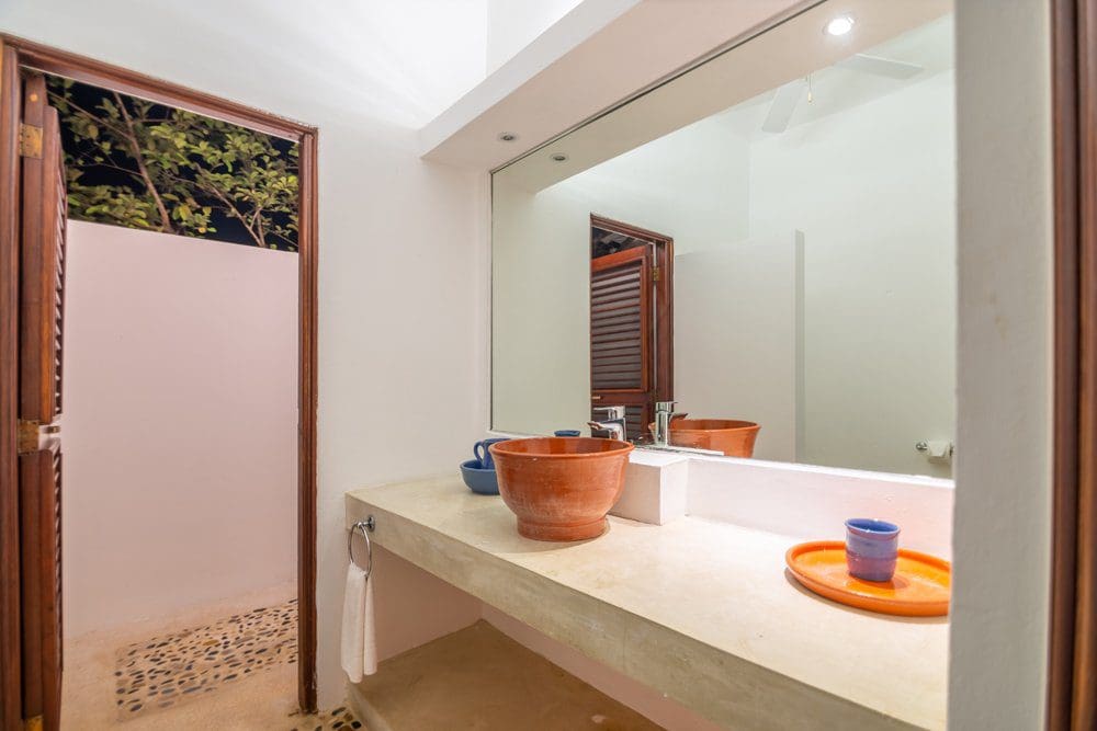 buyDRproperty Bathroom with terracotta sink and open door to outdoor shower at Villa LUNA Sosua Real Estate