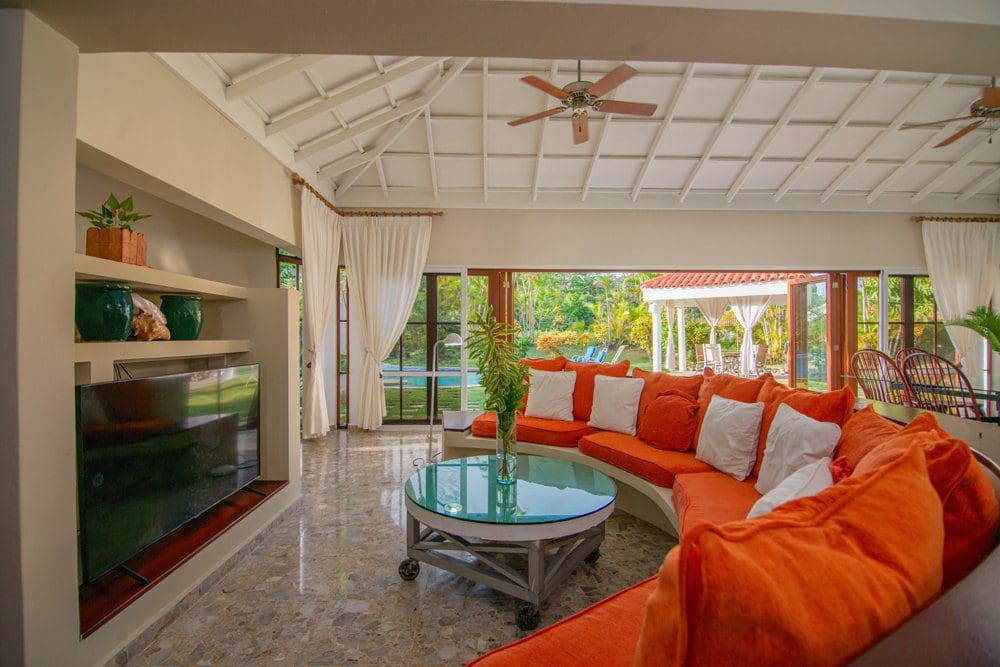 buyDRproperty Living room with orange sofa and view of the pool at Villa Luna, Sea Horse Ranch. Sosua Real Estate