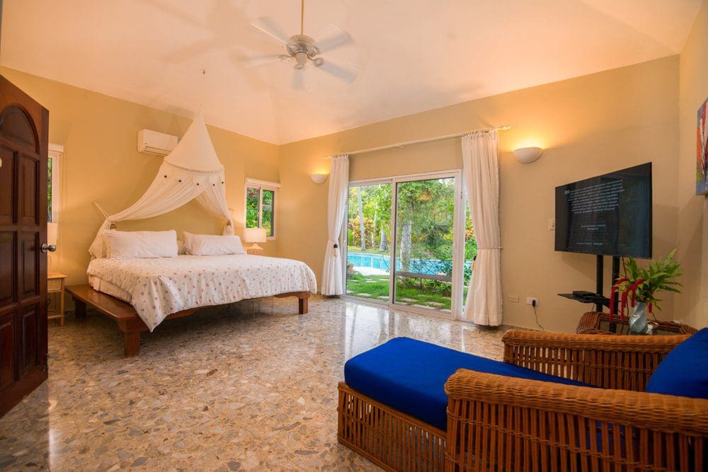 buyDRproperty Luxury bedroom at Villa LUNA, featuring a canopy bed, pool view, and Sea Horse Ranch location. Sosua Real Estate