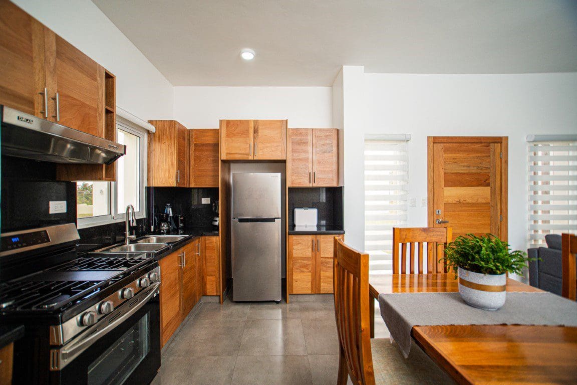 buyDRproperty Modern kitchen in a countryside villa for sale with wooden cabinets and stainless steel appliances. Sosua Real Estate