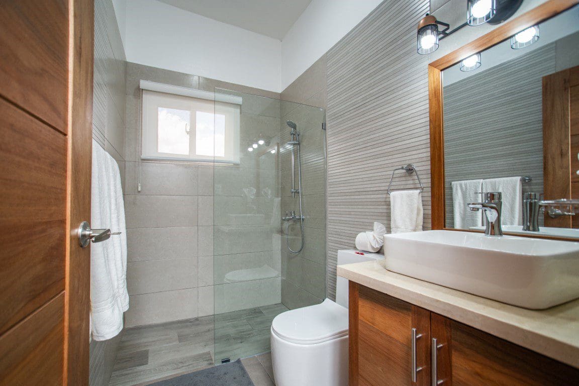 buyDRproperty Modern bathroom in a Countryside Villa For Sale with glass shower, sink, and wood vanity. Sosua Real Estate