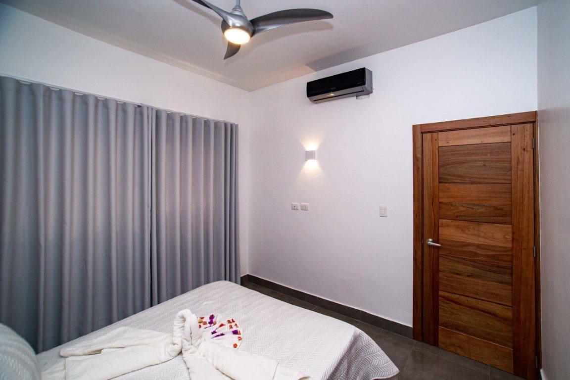 buyDRproperty Bedroom in a Countryside Villa For Sale featuring a bed, curtains, and wooden door. Sosua Real Estate