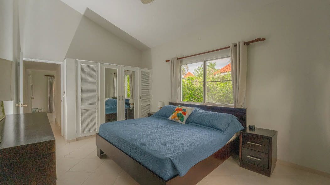 buyDRproperty Bedroom in a beautiful 3 bedroom villa with blue bedding and a large window. Sosua Real Estate
