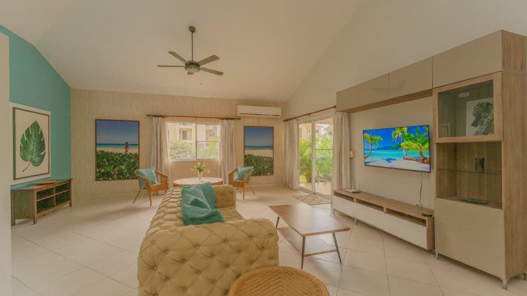 buyDRproperty Living room of a beautiful 3 bedroom villa with beach-themed artwork and a large TV. Sosua Real Estate