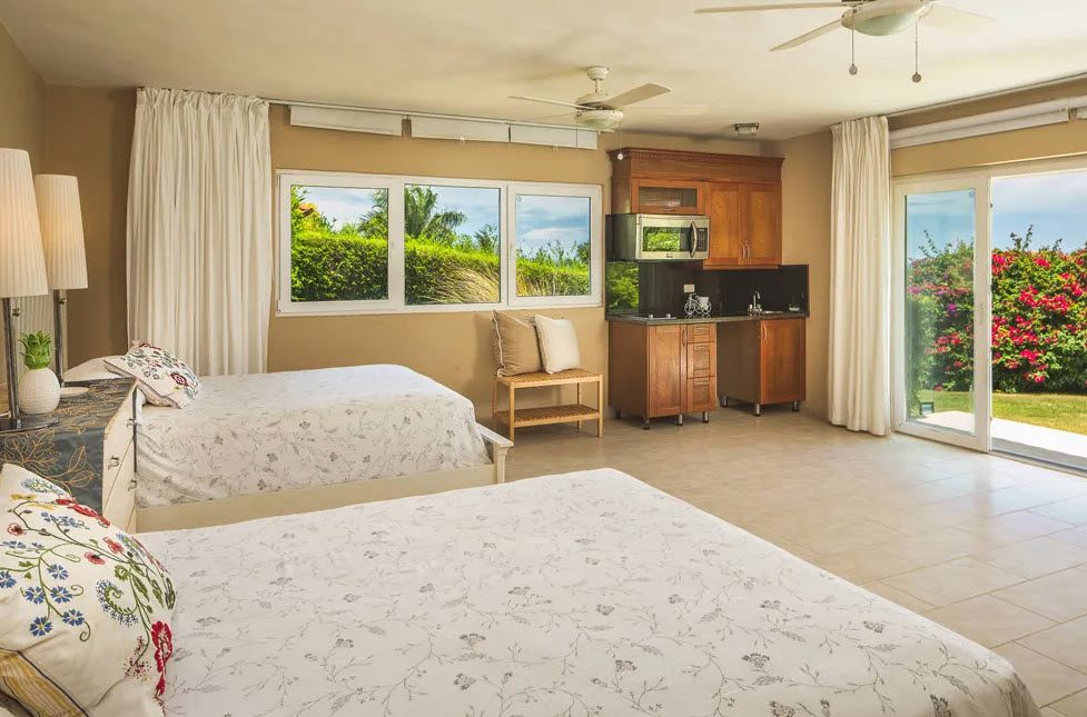 buyDRproperty Bedroom in a beautiful 5-bedroom villa for sale in Residential Hispaniola with two beds, a kitchenette, and garden view. Sosua Real Estate