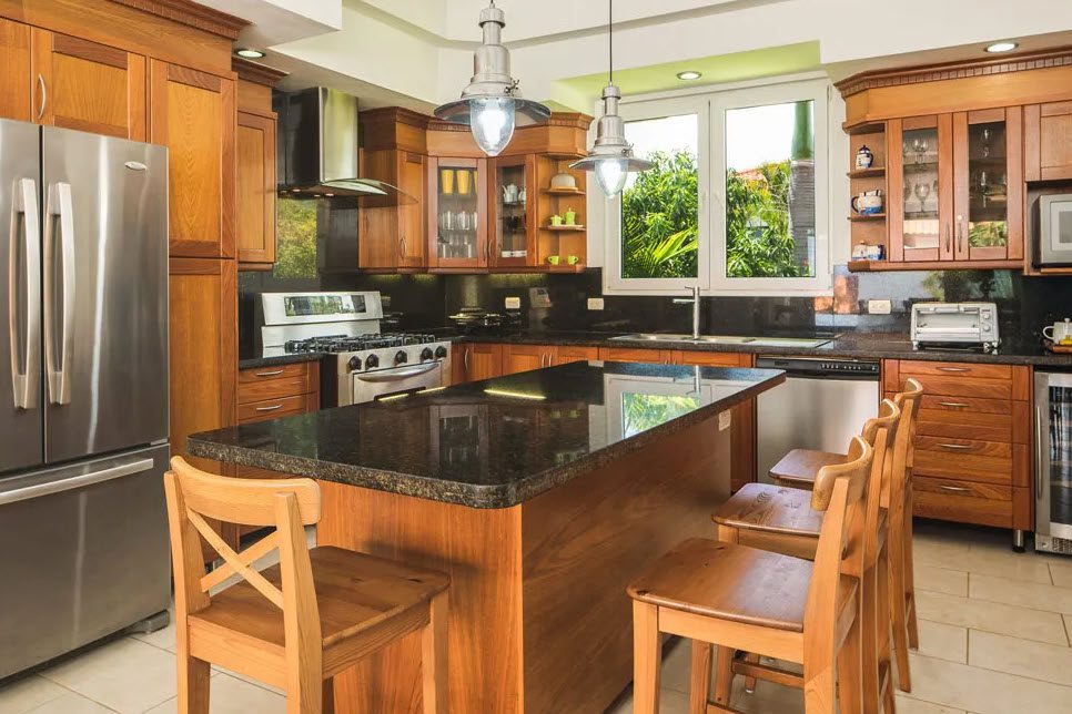 buyDRproperty Beautiful kitchen with wooden cabinets and island in a Residential Hispaniola villa. Sosua Real Estate